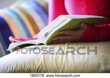 Stock Photo - Woman holding book on pillow. Fotosearch