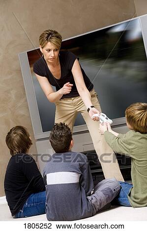 Woman stopping boys from playing video game View Large Photo Image Stock Image - Woman stopping boys from playing video game. Fotosearch