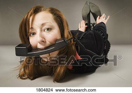 Woman tied with telephone cord, holding receiver in mouth View Large Photo Image Picture - Woman tied with telephone cord, holding receiver in mouth. Fotosearch