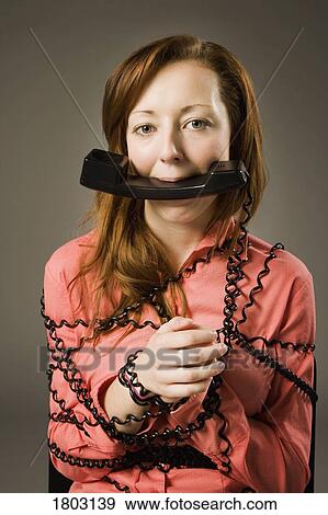 Woman wrapped in telephone cord, holding receiver in mouth View Large Photo Image Stock Photo - Woman wrapped in telephone cord, holding receiver in mouth. Fotosearch