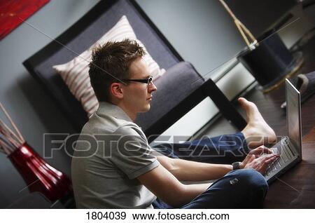 Stock Photo - Young adult male using a lap top computer. Fotosearch