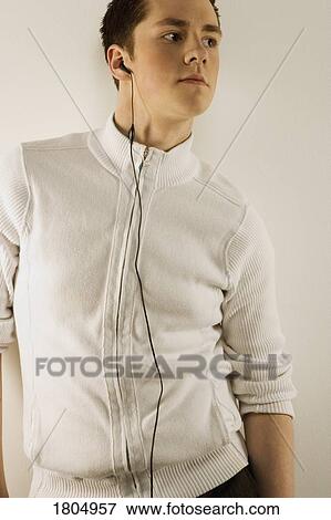 Stock Photo - Young man modelling a mock turtleneck zip-up sweater and earbud. Fotosearch
