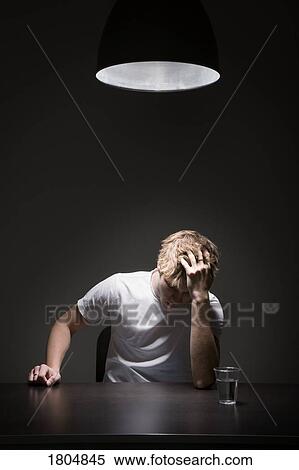 Young man sitting at a table View Large Photo Image Stock Photography - Young man sitting at a table. Fotosearch
