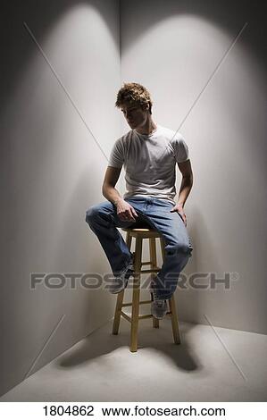 Young man sitting on a stool View Large Photo Image Stock Image - Young man sitting on a stool. Fotosearch