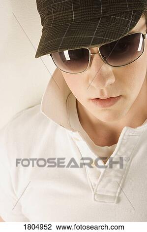 Young man wearing a hat and sunglasses View Large Photo Image Stock Image - Young man wearing a hat and sunglasses. Fotosearch