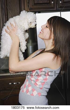 Stock Photography - Young woman holding puppy, smiling. Fotosearch