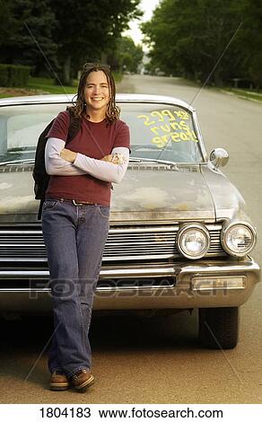 Young woman leaning against a retro car View Large Photo Image Stock Image - Young woman leaning against a retro car. Fotosearch