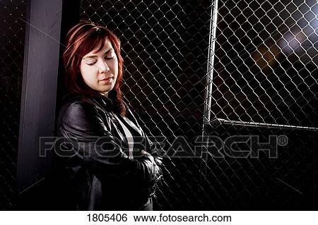 Stock Photograph - Young woman standing with arms crossed looking down. Fotosearch