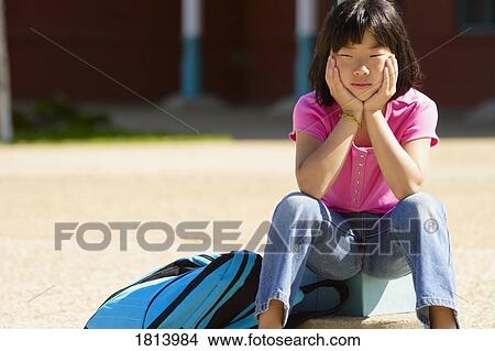 A thoughtful girl sitting with bag View Large Photo Image Picture - A thoughtful girl sitting with bag. Fotosearch