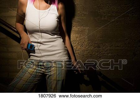 Stock Photograph - A woman listening to MP3 player on steps. Fotosearch