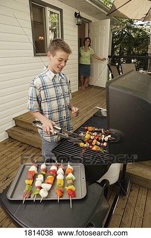 Stock Photo - Boy barbecuing outdoors. Fotosearch