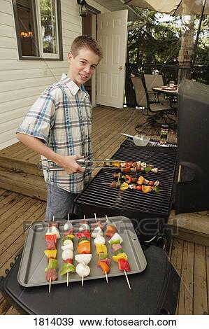 Stock Photo - Boy barbecuing outdoors. Fotosearch
