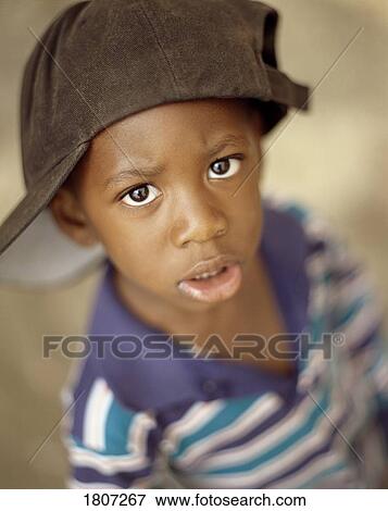 Stock Photo - Boy wearing over sized baseball cap. Fotosearch