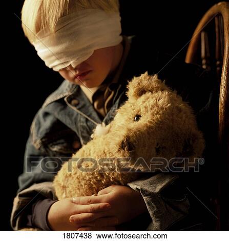 Stock Photo - Boy with bandage on eyes and holding teddy bear. Fotosearch