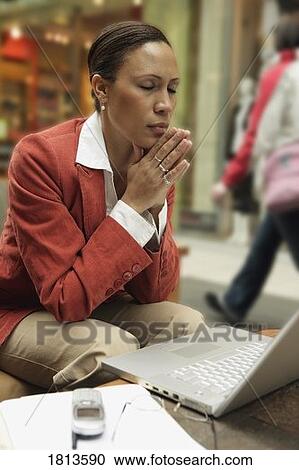 Stock Image - Business woman sitting with laptop and cell phone. Fotosearch