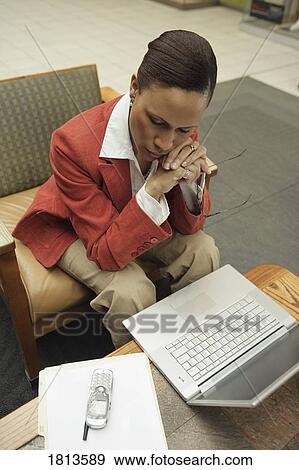 Stock Photo - Business woman working with laptop and cell phone. Fotosearch
