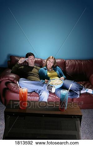Stock Image - Front view of a couple watching television. Fotosearch
