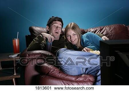 Stock Image - Front view of a couple watching television. Fotosearch