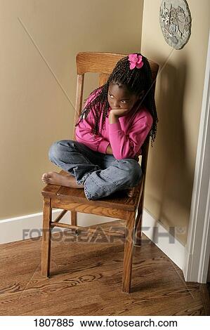 Stock Photography - Girl on a chair in the corner. Fotosearch