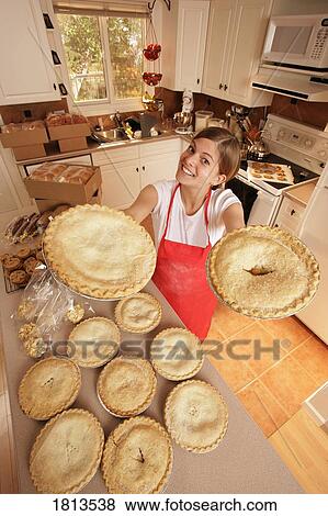 Stock Photo - Girl standing in kitchen with pies. Fotosearch