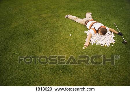 Stock Photo - High angle view of a man lying on golf balls. Fotosearch