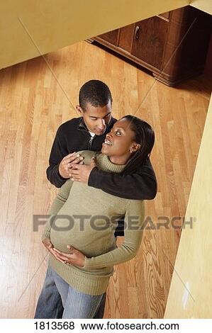 Stock Photo - High angle view of pregnant couple standing indoors. Fotosearch