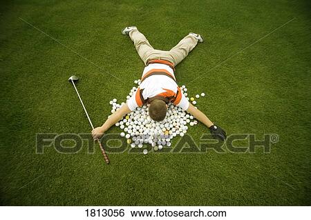 Stock Photograph - Man lying on golf balls. Fotosearch