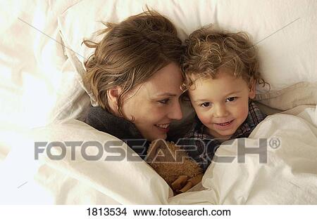 Picture - Mother and son laying in bed. Fotosearch