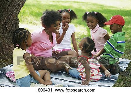 Stock Image - Mother with her children gathered around her at the park. Fotosearch