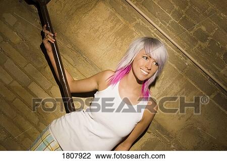 Stock Image - Portrait of woman smiling and leaning against railing. Fotosearch