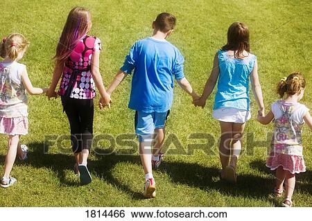 Stock Photograph - Rear view of a kids walking and holding hands. Fotosearch