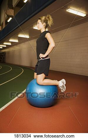 Picture - Side view of woman on exercise ball. Fotosearch