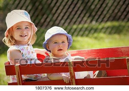 Stock Photograph - Sisters sitting in a wagon. Fotosearch