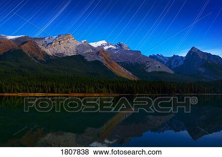 Stock Photo - Starry night panoramic of mountains and lake, Maligne Lake, Jasper National Park, Alberta, Canada. Fotosearch