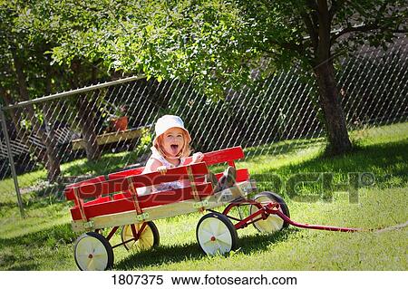Toddler sitting in a red wagon View Large Photo Image Stock Photography - Toddler sitting in a red wagon. Fotosearch