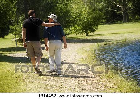 Stock Image - Two men walking in the park. Fotosearch
