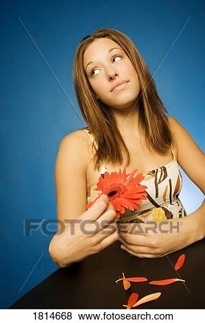 Stock Photo - Woman pulling petals off daisy. Fotosearch