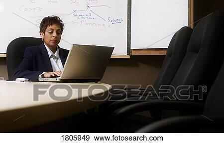 Stock Photo - Woman working on laptop in boardroom. Fotosearch