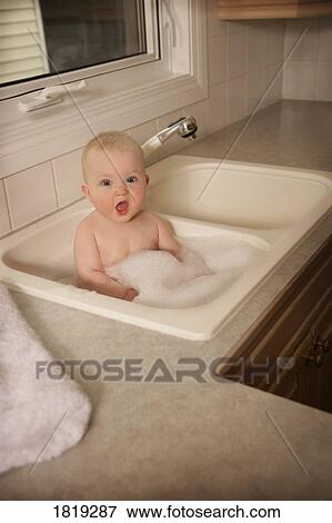 A baby having a bath in the kitchen sink View Large Photo Image Stock Photo - A baby having a bath in the kitchen sink. Fotosearch