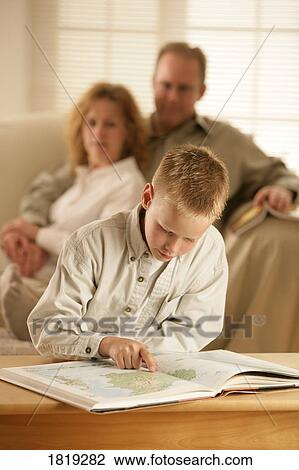 Stock Image - A boy looking at an atlas. Fotosearch