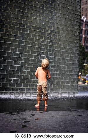 Stock Photo - A boy standing beside a wall fountain, Chicago, Illinois, USA. Fotosearch