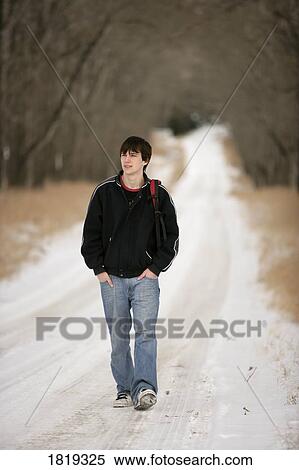 Stock Photography - A teenage boy walking on a snow-covered path. Fotosearch