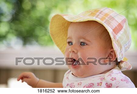 Stock Image - Baby girl wearing sunhat. Fotosearch