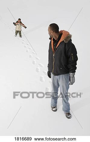 Boy following his dad's footprints in the snow View Large Photo Image Stock Photo - Boy following his dad's footprints in the snow. Fotosearch