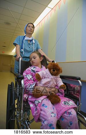 Stock Image - Doctor pushing a girl in a wheelchair. Fotosearch
