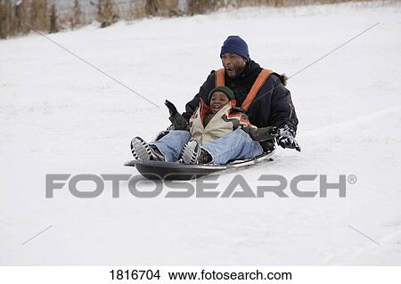 Picture - Father and son sledding on snow. Fotosearch