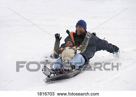 Stock Image - Father and son sledding on snow. Fotosearch