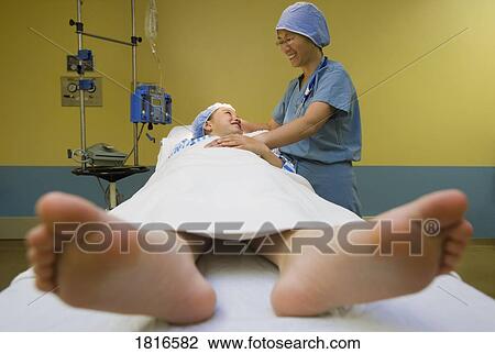 Stock Image - Female patient on an operating table under a doctor's supervision. Fotosearch