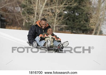 Stock Image - Front view of father and son on sled. Fotosearch