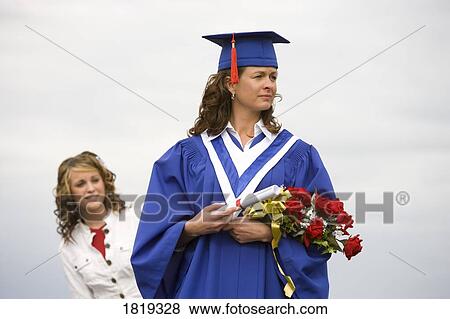 Stock Photo - Graduate holding diploma and flowers. Fotosearch